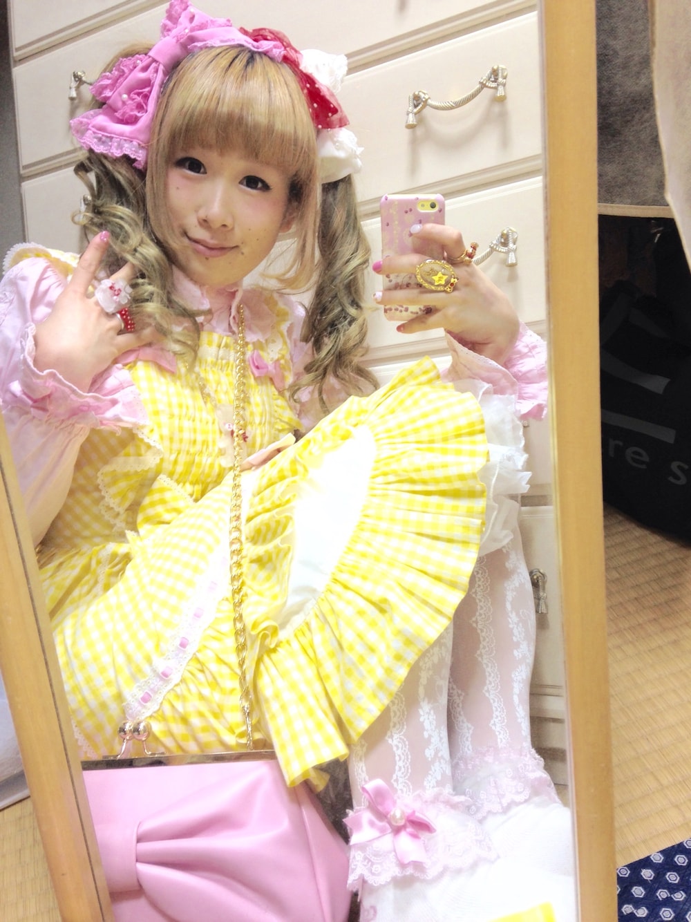 イエロー系のワンピース、ピンク系のシャツ/ブラウス、ピンク系のショルダーバッグを着用したレディースの冬コーディネートの1枚目の写真