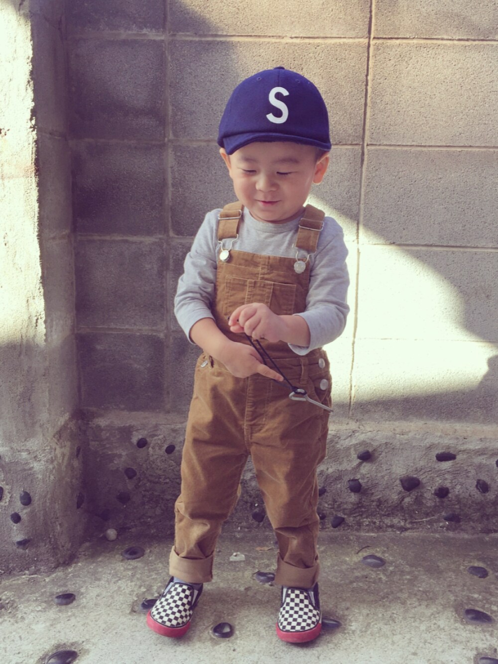 ブラウン系のサロペット/オーバーオール、ブルー系のキャップを着用したキッズの秋コーディネートの1枚目の写真