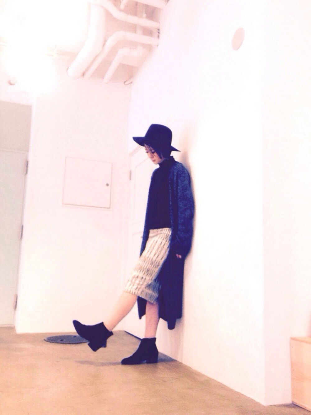 ブラック系のブーツ、ホワイト系のスカート、ブラック系のニット/セーターを着用したレディースの春コーディネートの1枚目の写真