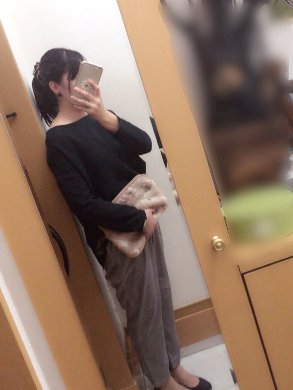 グリーン系のトップス、ピンク系のクラッチバッグ、グレー系のパンツを着用したレディースの秋コーディネートの1枚目の写真