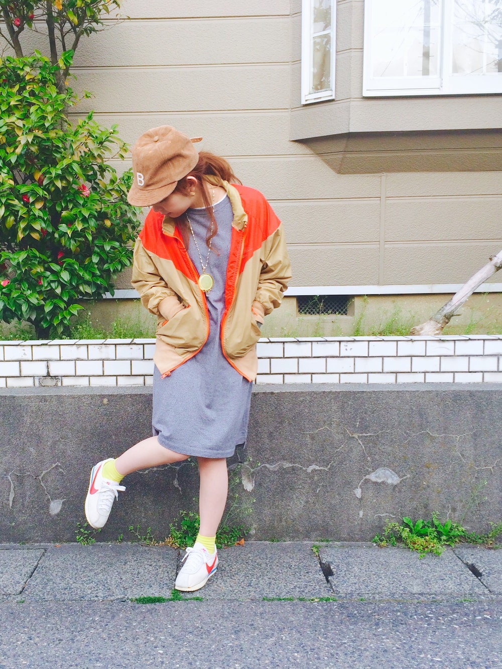 ベージュ系のナイロンジャケット、ホワイト系のスニーカー、グレー系のワンピースを着用したレディースの春コーディネートの1枚目の写真