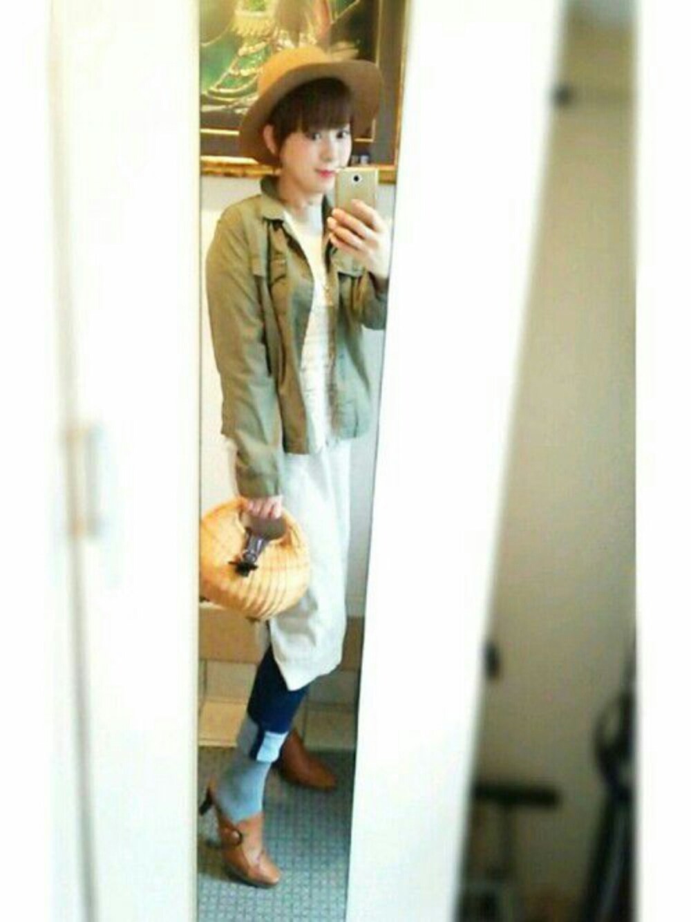 ベージュ系のワンピース、グリーン系のミリタリージャケット、ベージュ系のかごバッグを着用したレディースの春コーディネートの1枚目の写真