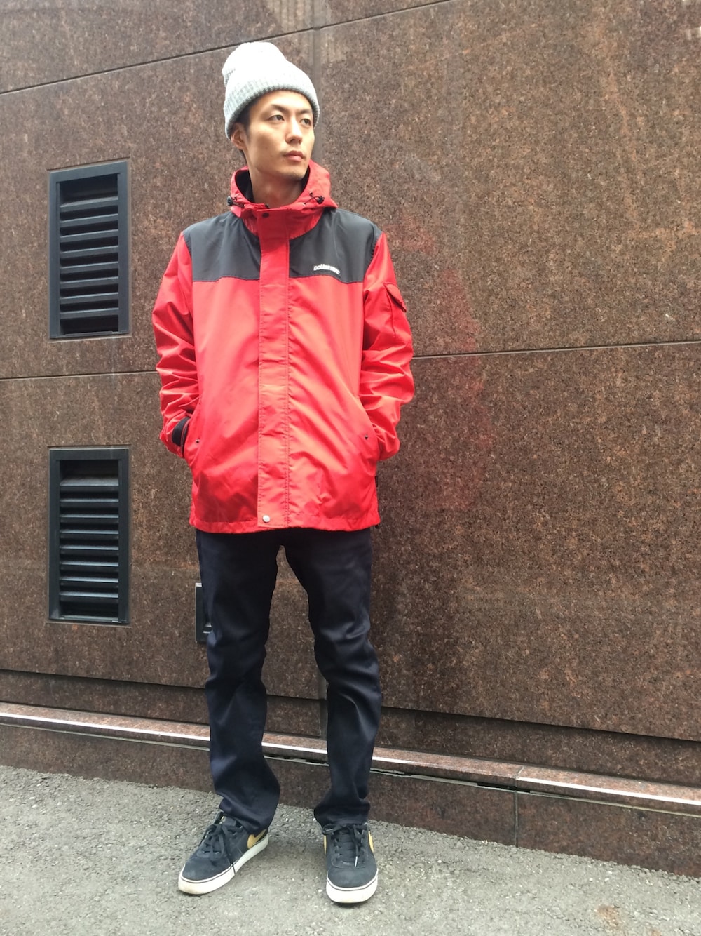 レッド系のマウンテンパーカー、ブラック系のチノパンツ、グレー系のニットキャップ/ビーニーを着用したメンズの秋コーディネートの1枚目の写真