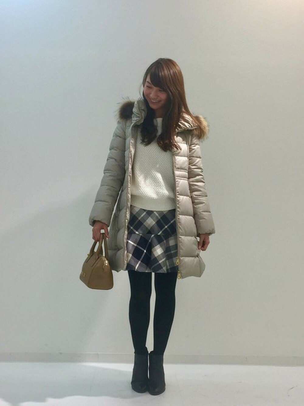 ベージュ系のその他アウター、ホワイト系のニット/セーター、ブルー系のスカートを着用したレディースの冬コーディネートの1枚目の写真
