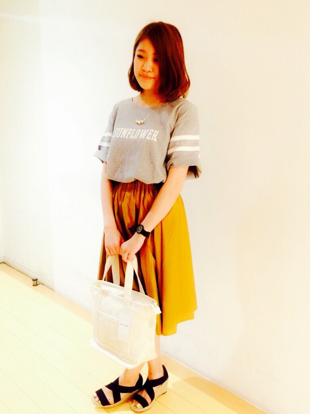 グレー系のTシャツ/カットソー、イエロー系のスカート、ホワイト系のトートバッグを着用したレディースの夏コーディネートの1枚目の写真