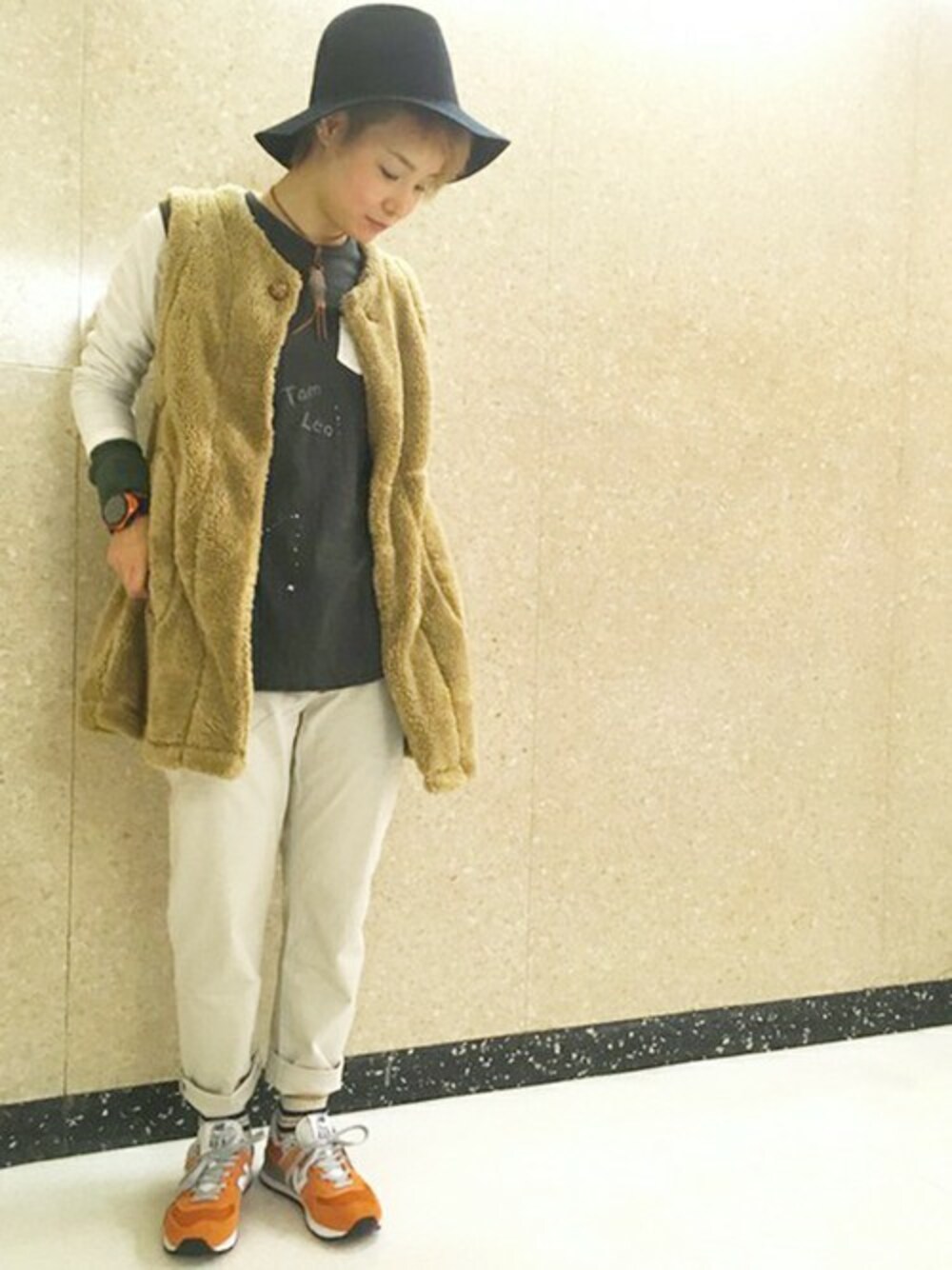 ベージュ系のベスト、グレー系のその他パンツ、オレンジ系のスニーカーを着用したレディースの秋コーディネートの1枚目の写真