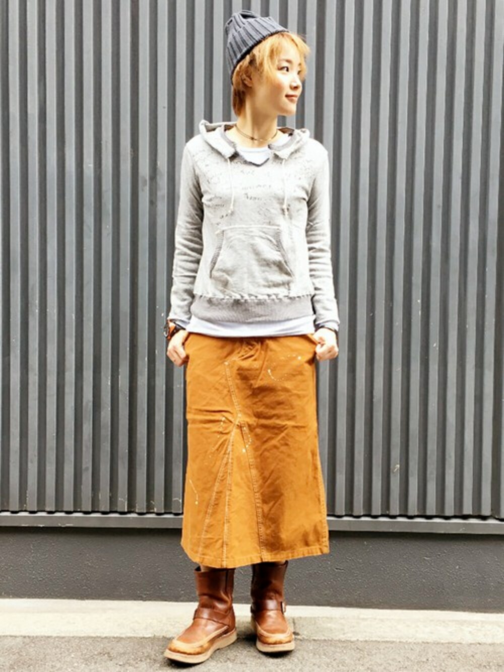 ブラウン系のスカート、グレー系のパーカー、ブラウン系のブーツを着用したレディースの秋コーディネートの1枚目の写真