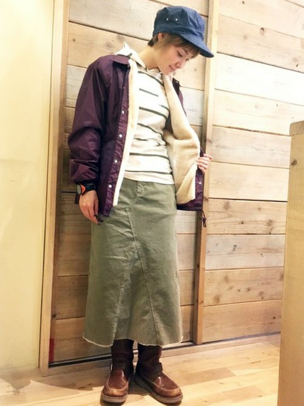 ベージュ系のスカート、パープル系のブルゾン、ベージュ系のパーカーを着用したレディースの冬コーディネートの1枚目の写真