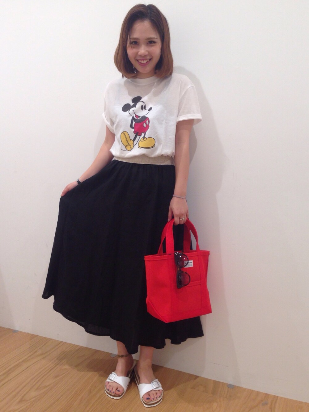 ブラック系のスカート、ホワイト系のTシャツ/カットソー、レッド系のトートバッグを着用したレディースの夏コーディネートの1枚目の写真