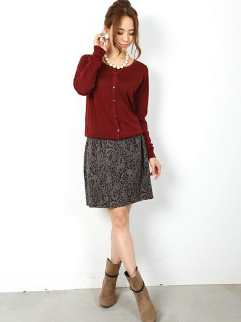 グレー系のスカート、レッド系のカーディガン/ボレロを着用したレディースの冬コーディネートの1枚目の写真