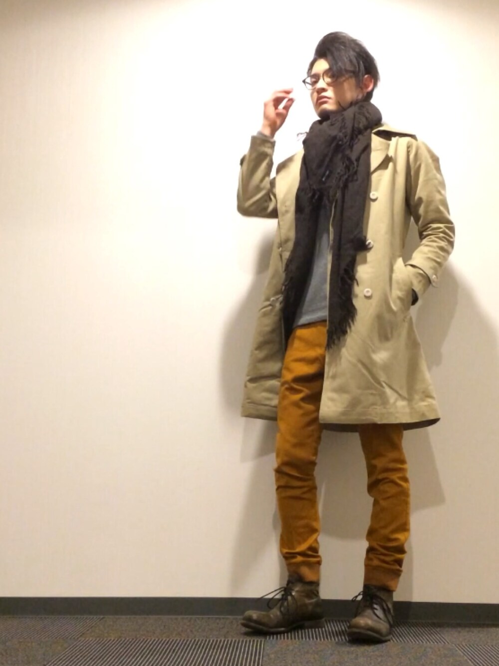ベージュ系のトレンチコート、イエロー系のスラックス、ブラウン系のブーツを着用したメンズの冬コーディネートの1枚目の写真
