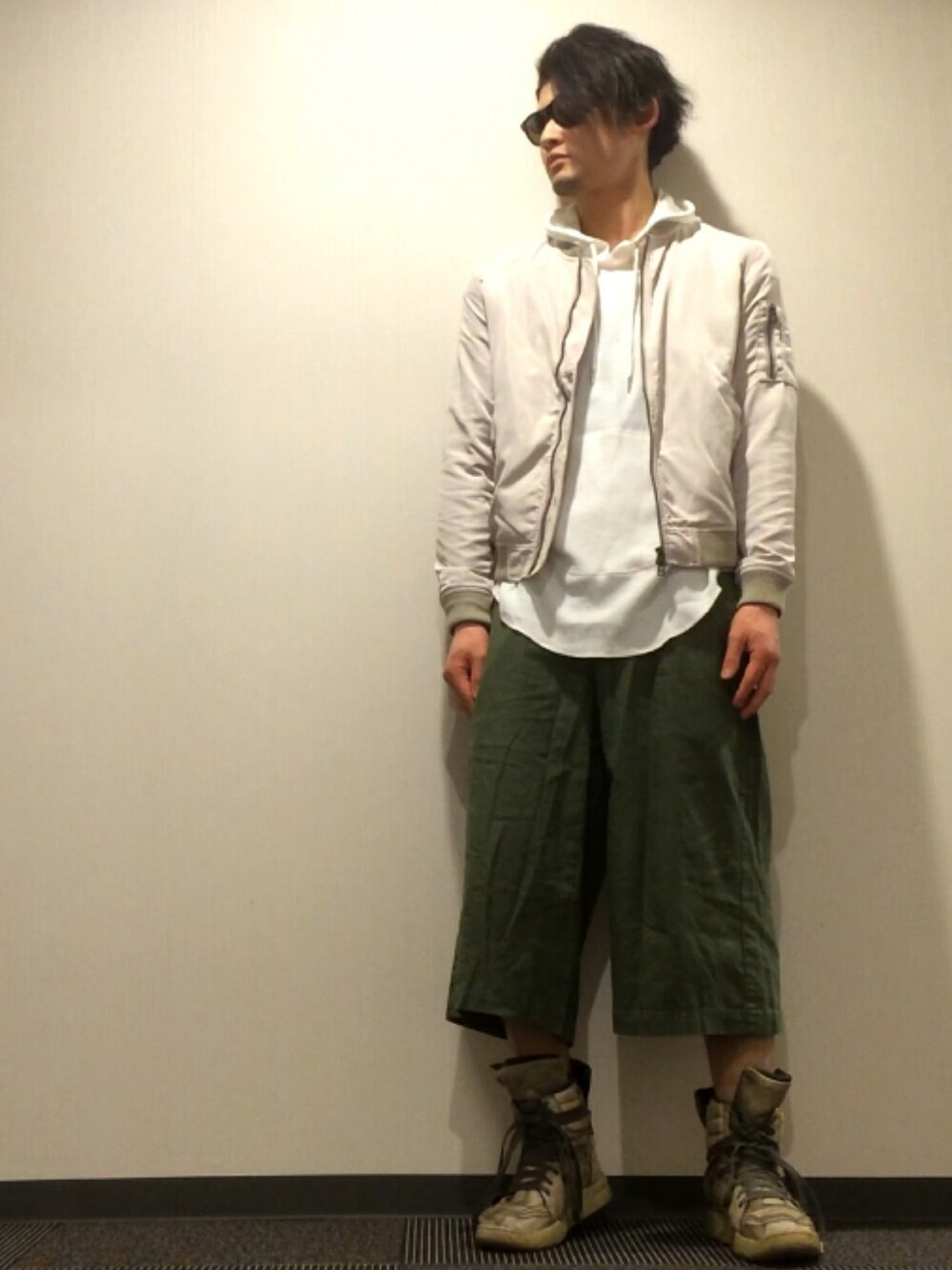 ホワイト系のミリタリージャケット、グリーン系のスラックス、ホワイト系のスニーカーを着用したメンズの春コーディネートの1枚目の写真
