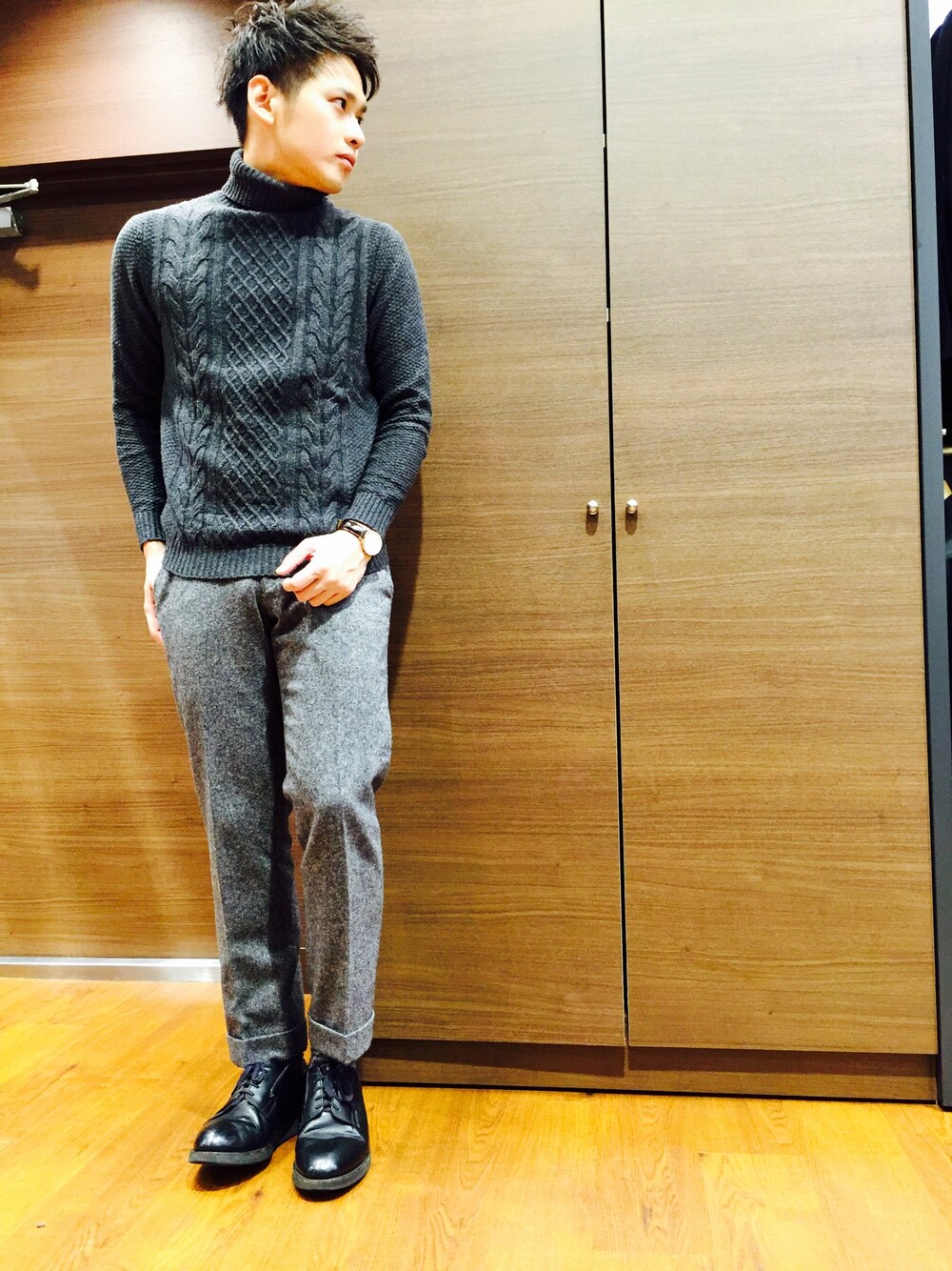 グレー系のニット/セーター、グレー系のスラックス、ブラック系のドレスシューズを着用したメンズの冬コーディネートの1枚目の写真