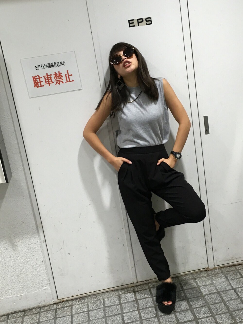 ブラック系のパンツ、グレー系のトップス、ブラウン系のサングラスを着用したレディースの秋コーディネートの1枚目の写真