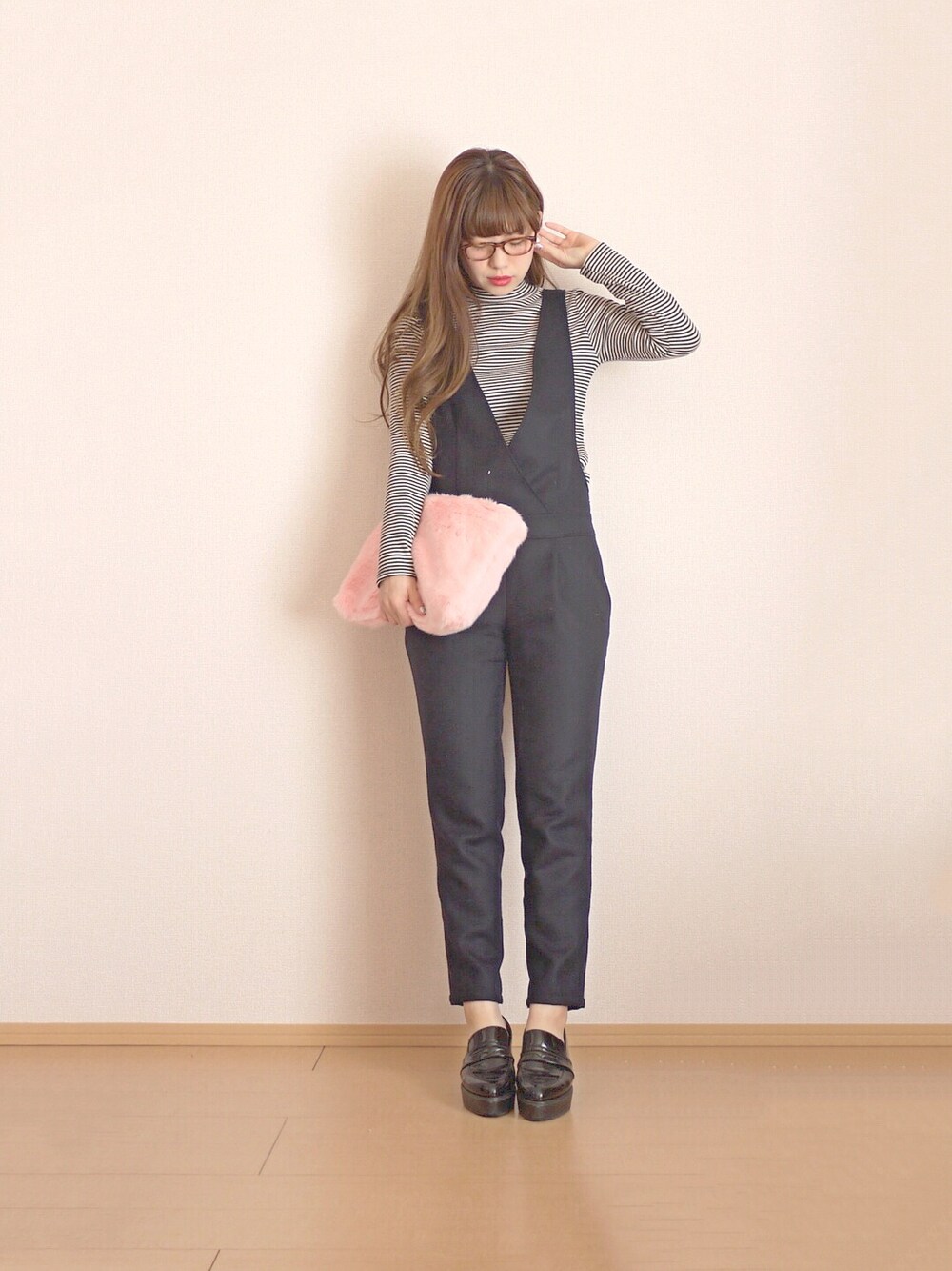 ピンク系のクラッチバッグ、ブラウン系のメガネ、ホワイト系のピアス（両耳用）を着用したレディースの冬コーディネートの1枚目の写真