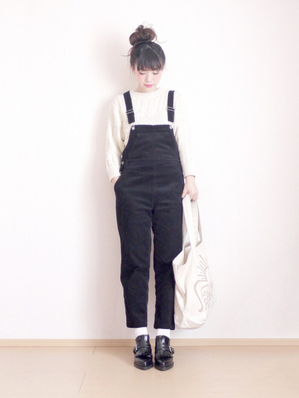 ブラック系のサロペット/オーバーオール、ホワイト系のニット/セーター、ベージュ系のトートバッグを着用したレディースの冬コーディネートの1枚目の写真