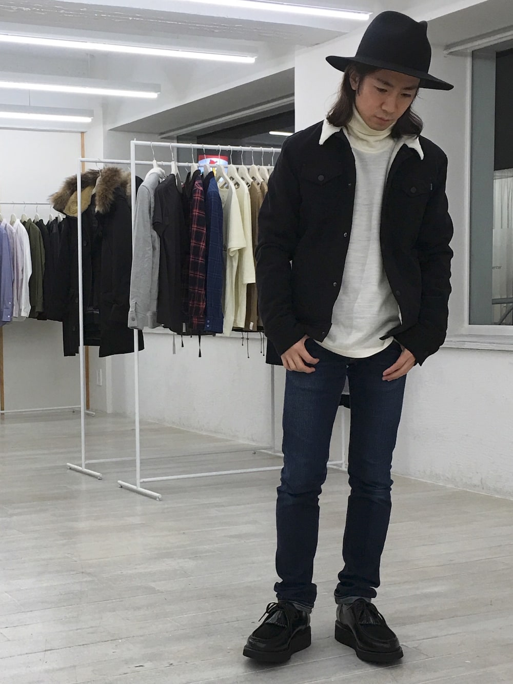 ブラック系のライダースジャケット、ベージュ系のTシャツ/カットソー、ブルー系のデニムパンツを着用したメンズの冬コーディネートの1枚目の写真