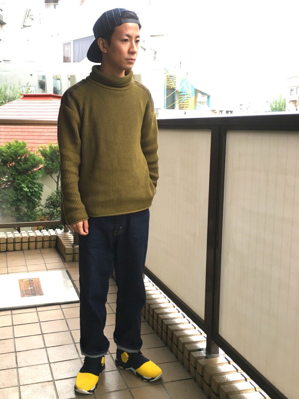 グリーン系のニット/セーター、ブルー系のデニムパンツ、イエロー系のスニーカーを着用したメンズの秋コーディネートの1枚目の写真