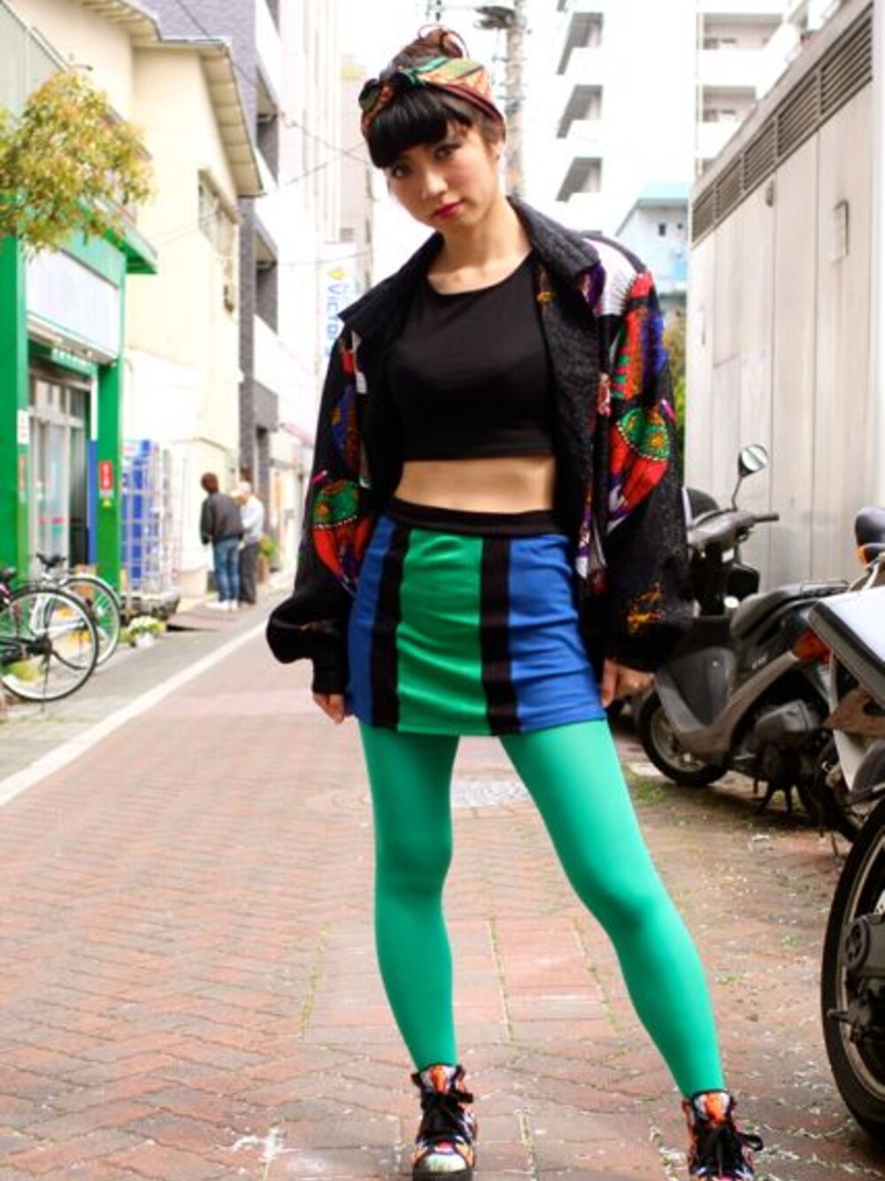 ブラック系のナイロンジャケット、ブルー系のスカート、オレンジ系のスニーカーを着用したレディースの春コーディネートの1枚目の写真