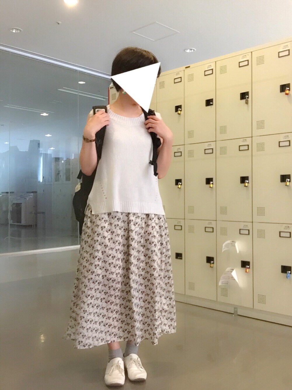 グレー系のトップス、ホワイト系のスカート、ホワイト系のシューズを着用したレディースの夏コーディネートの1枚目の写真