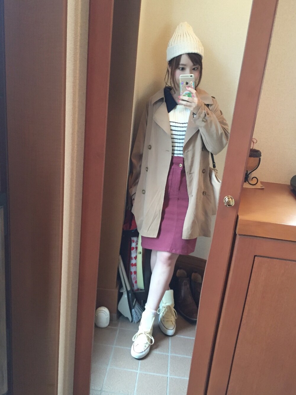 ベージュ系のトレンチコート、ホワイト系のニット/セーター、レッド系のスカートを着用したレディースの秋コーディネートの1枚目の写真