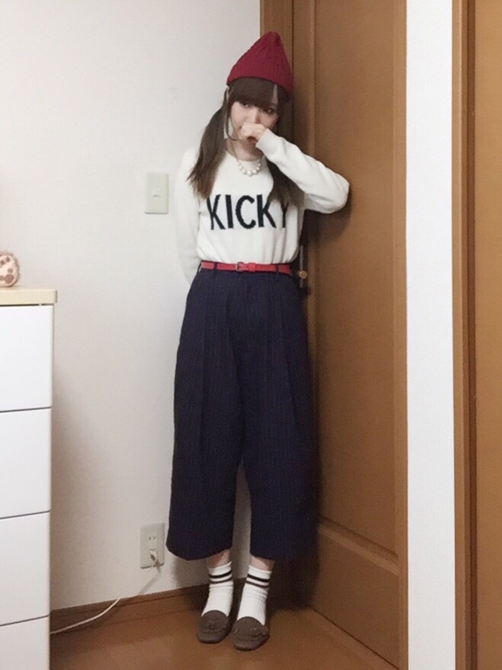 ブラウン系のダッフルコート、ホワイト系のニット/セーター、レッド系のパンツを着用したレディースの冬コーディネートの1枚目の写真