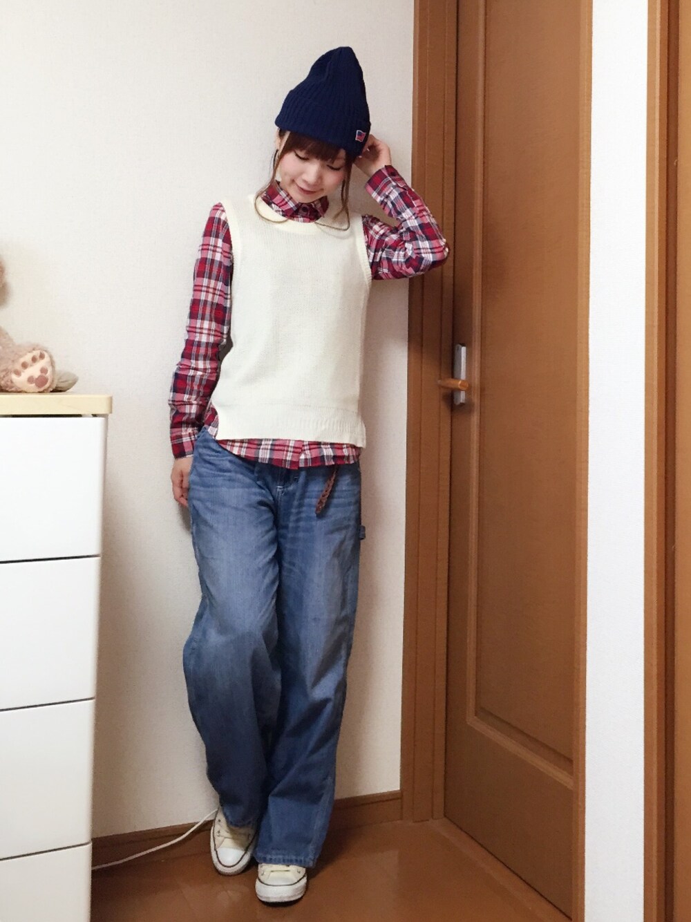 ホワイト系のベスト、ブルー系のデニムパンツ、ホワイト系のスニーカーを着用したレディースの秋コーディネートの1枚目の写真