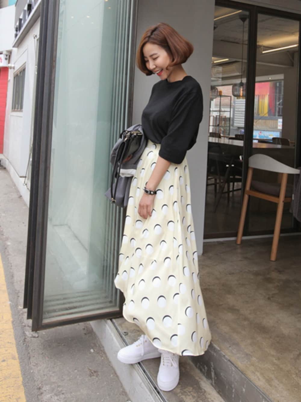 ブラック系のTシャツ/カットソー、イエロー系のスカート、ブラック系のブレスレットを着用したレディースの春コーディネートの1枚目の写真