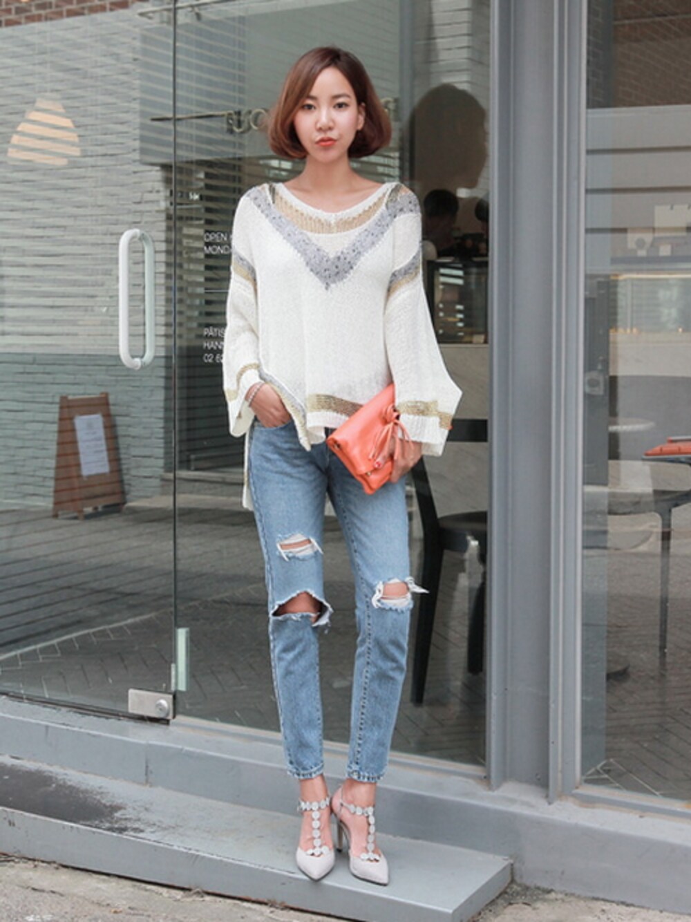 ホワイト系のニット/セーター、ブルー系のデニムパンツ、オレンジ系のハンドバッグを着用したレディースの夏コーディネートの1枚目の写真