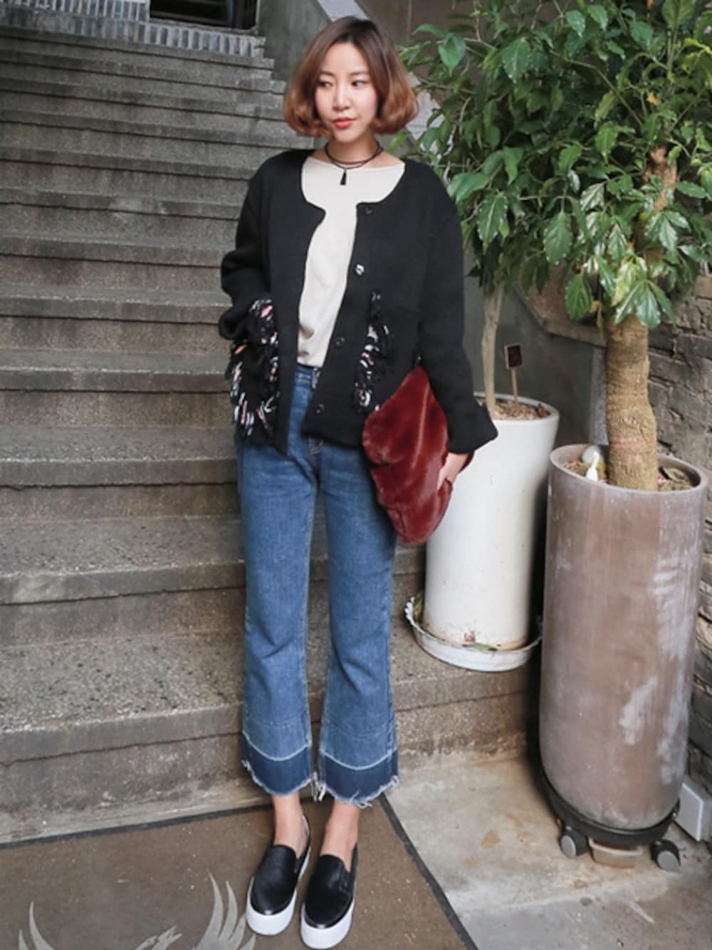 ブラック系のノーカラージャケット、ブルー系のデニムパンツ、レッド系のクラッチバッグを着用したレディースの秋コーディネートの1枚目の写真