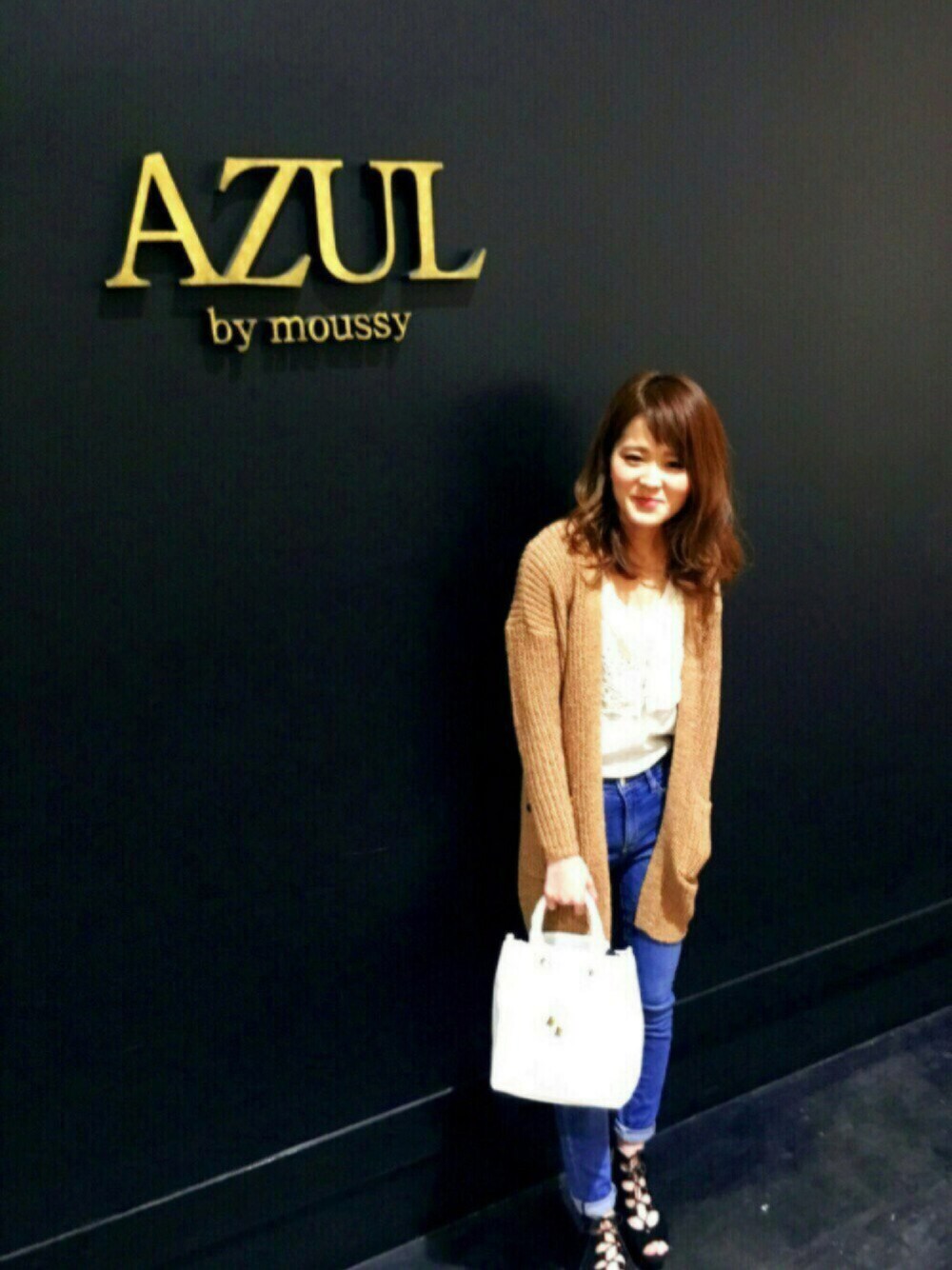 ブルー系のデニムパンツ、ホワイト系のカーディガン/ボレロ、ホワイト系のタンクトップを着用したレディースの春コーディネートの1枚目の写真