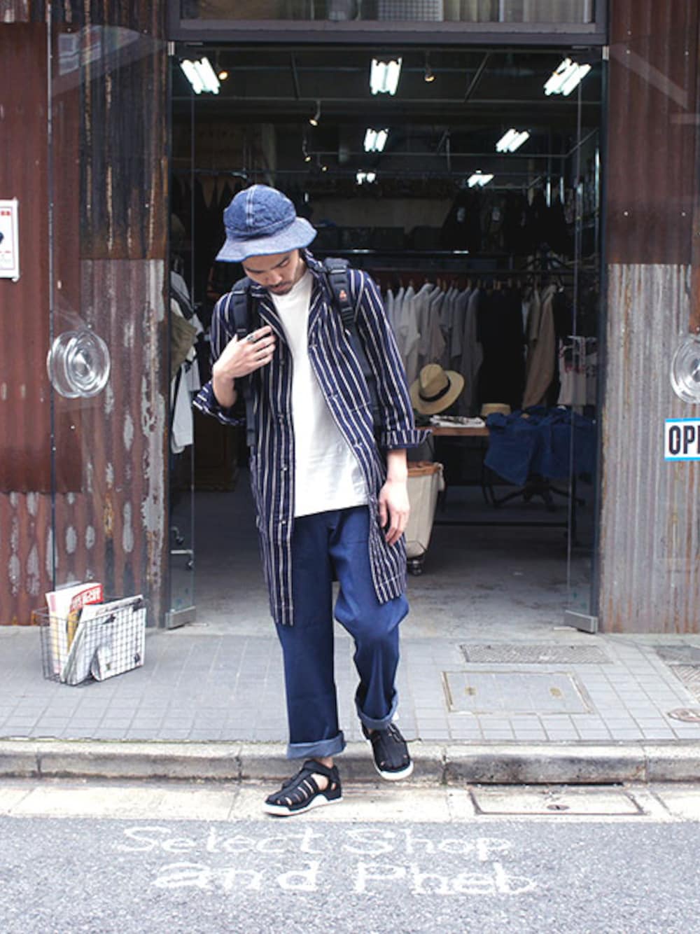 ブルー系のステンカラーコート、グレー系のTシャツ/カットソー、ブルー系のデニムパンツを着用したメンズの春コーディネートの1枚目の写真