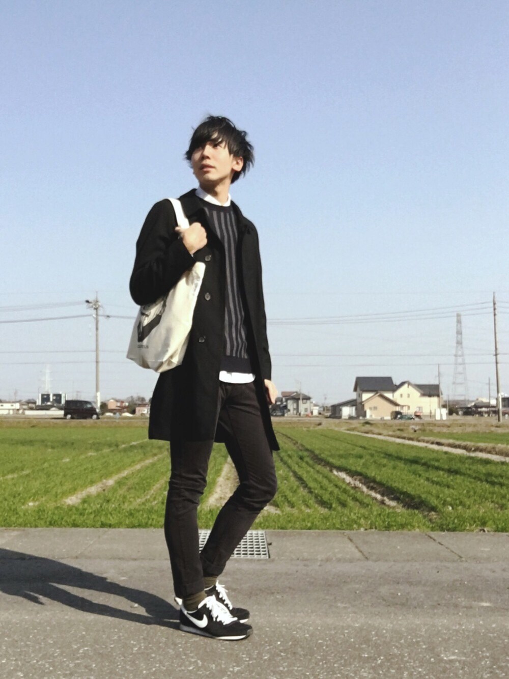 ブラック系のステンカラーコート、ブルー系のニット/セーター、ホワイト系のシャツ/ブラウスを着用したメンズの冬コーディネートの1枚目の写真