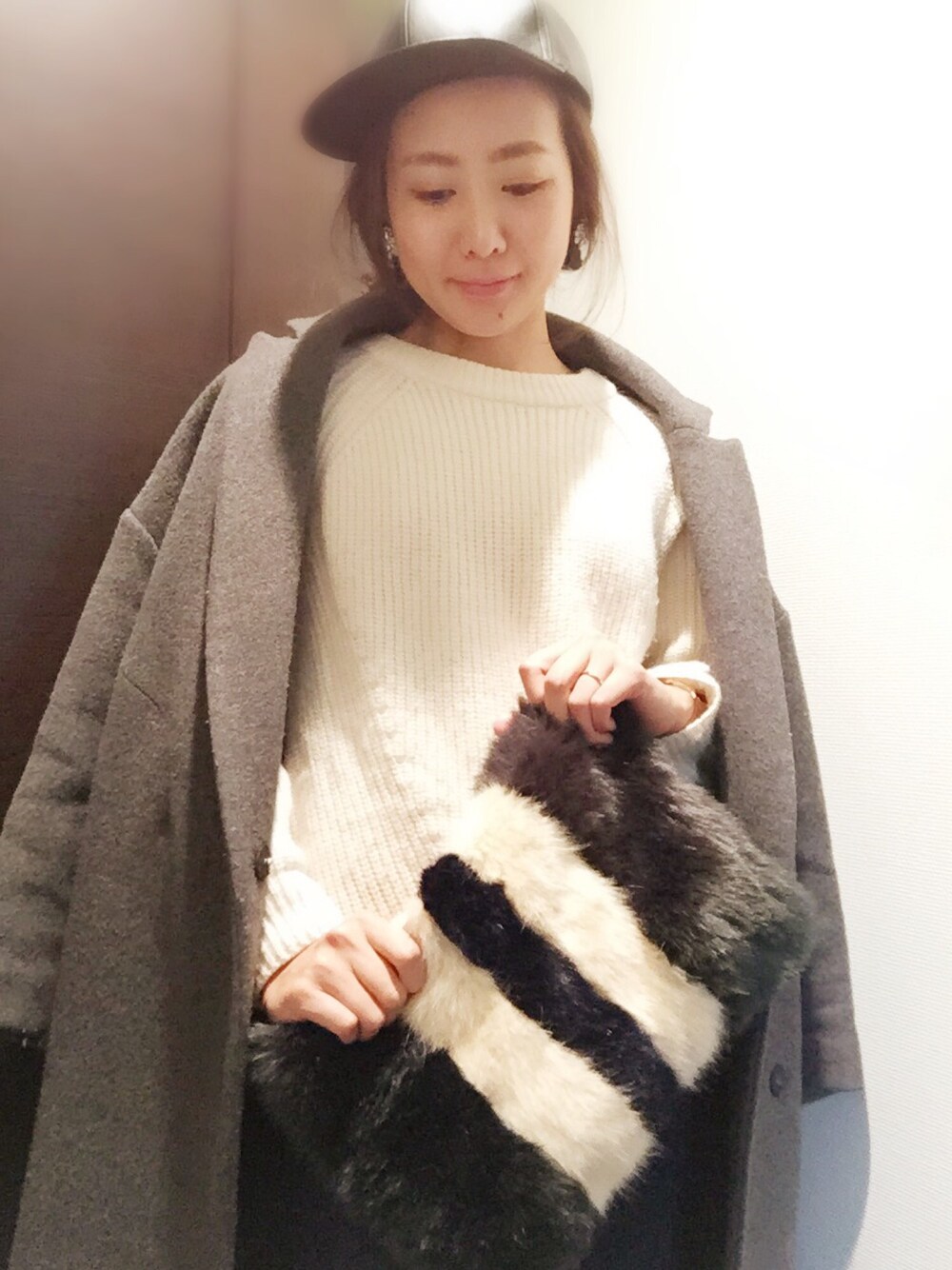 グレー系のジャケット/アウター、ホワイト系のニット/セーター、グリーン系のクラッチバッグを着用したレディースの冬コーディネートの1枚目の写真