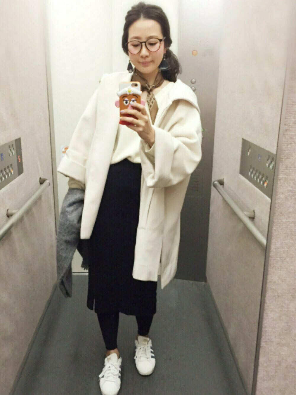 ホワイト系のニット/セーター、ブラック系のスカート、ホワイト系のステンカラーコートを着用したレディースの春コーディネートの1枚目の写真