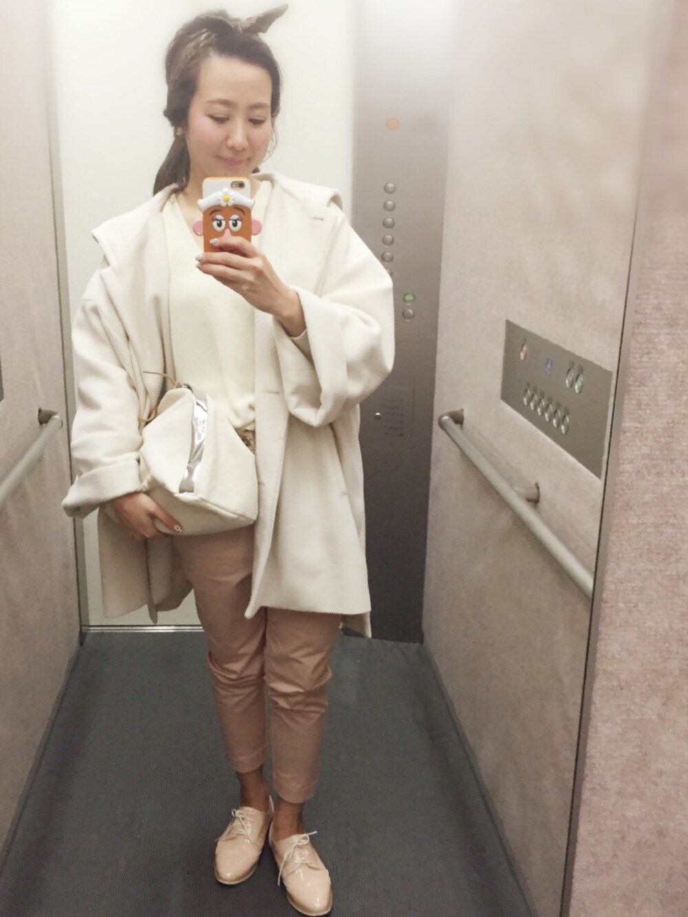 ホワイト系のステンカラーコート、ホワイト系のニット/セーター、ピンク系のドレスシューズを着用したレディースの冬コーディネートの1枚目の写真