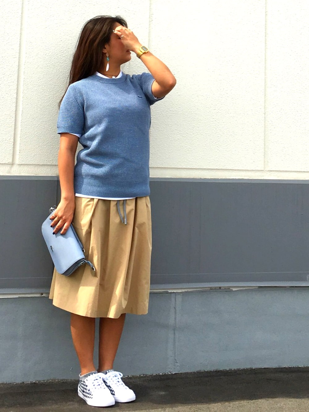 ブルー系のニット/セーター、ホワイト系のポロシャツ、ベージュ系のスカートを着用したレディースの春コーディネートの1枚目の写真
