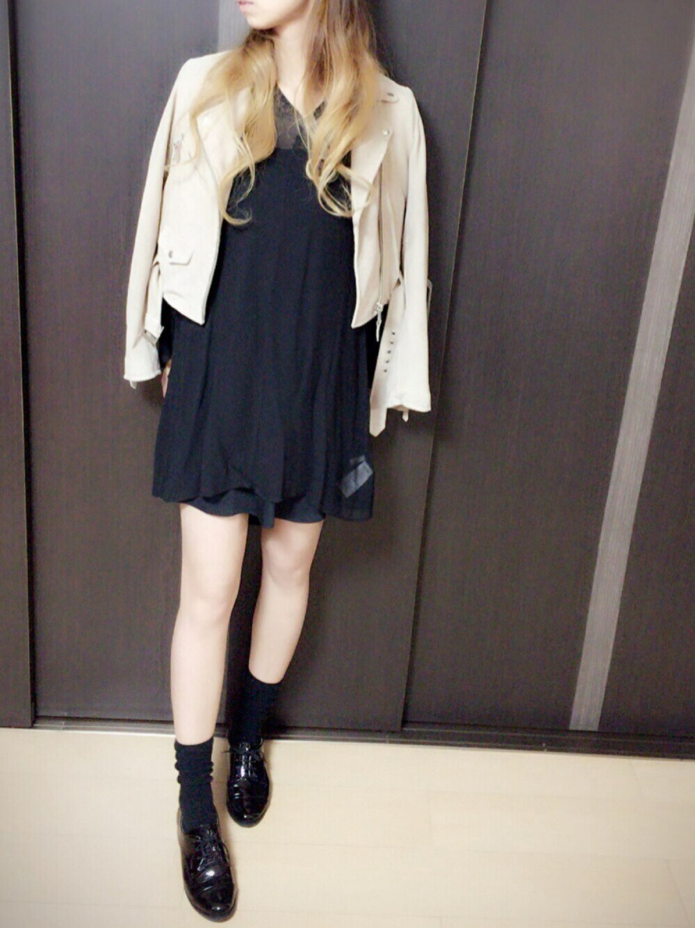 ベージュ系のライダースジャケット、ブラック系のワンピース、ブラック系のパンプスを着用したレディースの秋コーディネートの1枚目の写真