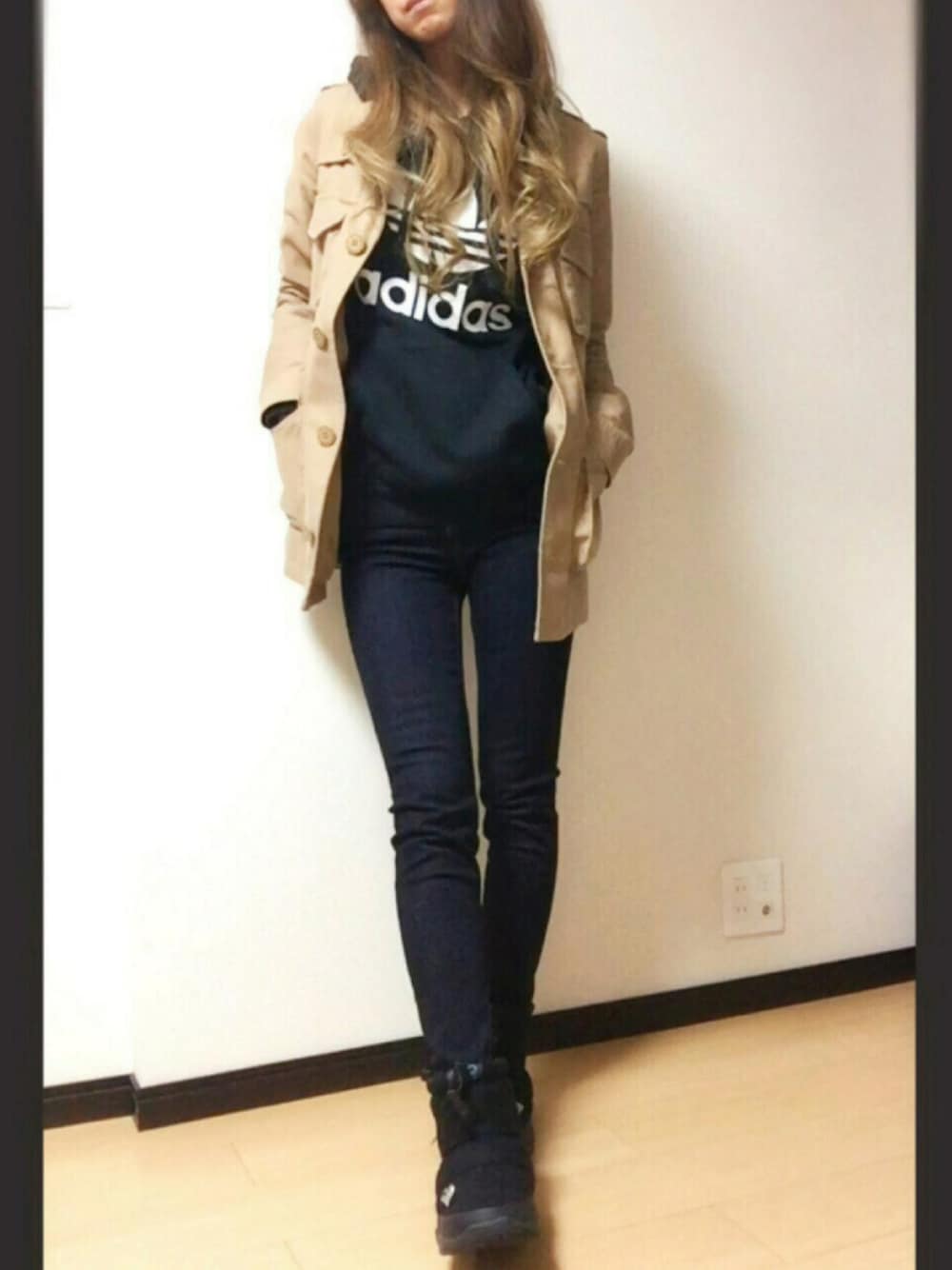 ベージュ系のミリタリージャケット、ブルー系のデニムパンツ、ブラック系のブーツを着用したレディースの秋コーディネートの1枚目の写真