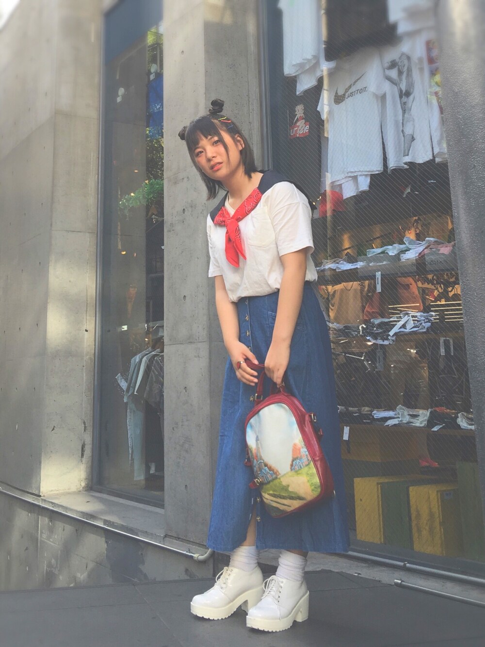ホワイト系のTシャツ/カットソー、ブルー系のデニムスカート、レッド系のバッグを着用したレディースの夏コーディネートの1枚目の写真