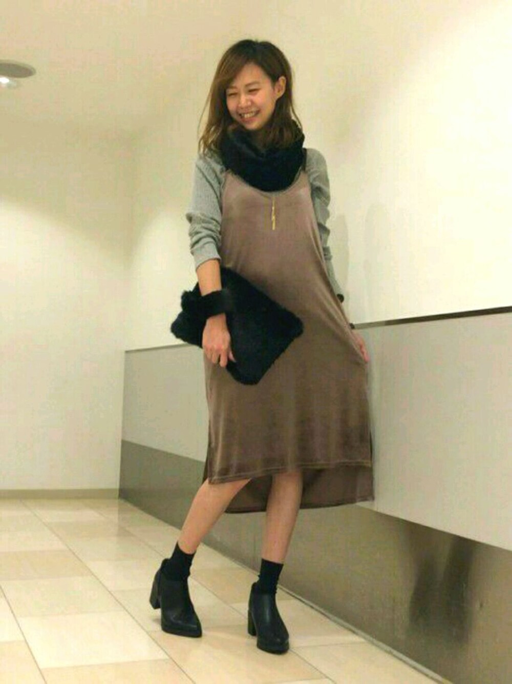 グレー系のワンピース、ブラック系のブーツ、ブラック系のハンドバッグを着用したレディースの秋コーディネートの1枚目の写真