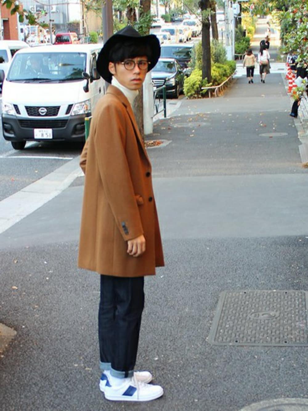 イエロー系のチェスターコート、ホワイト系のニット/セーター、ブルー系のデニムパンツを着用したメンズの秋コーディネートの1枚目の写真