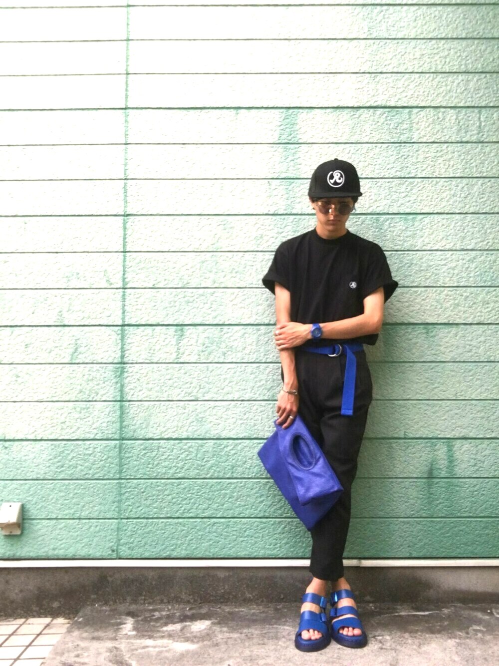 ブラック系のTシャツ/カットソー、ブルー系のクラッチバッグ、ブルー系のサンダルを着用したメンズの夏コーディネートの1枚目の写真