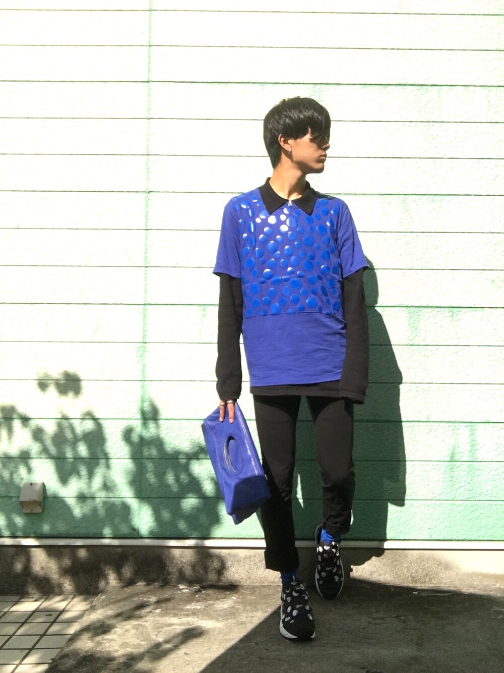ブルー系のTシャツ/カットソー、ブラック系のTシャツ/カットソー、ブルー系のクラッチバッグを着用したメンズの秋コーディネートの1枚目の写真