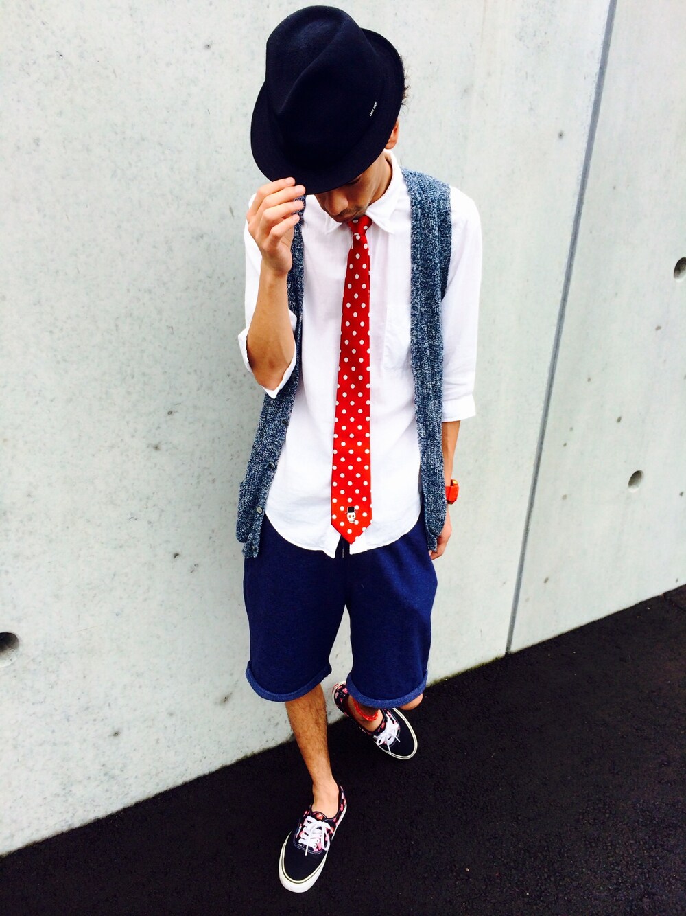 ブルー系のベスト、ブラック系のスニーカー、レッド系のネクタイを着用したメンズの夏コーディネートの1枚目の写真