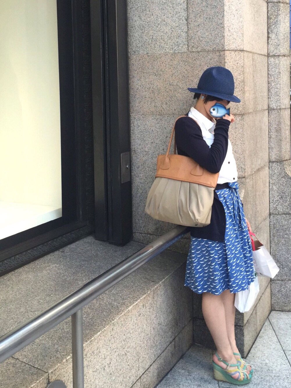 ブラウン系のバッグ、ブルー系のスカート、ブルー系のサンダルを着用したレディースの夏コーディネートの1枚目の写真
