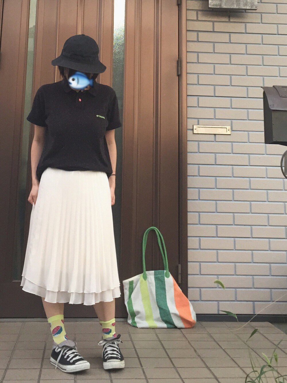 ブラック系のポロシャツ、ホワイト系のスカート、ブラック系のスニーカーを着用したレディースの夏コーディネートの1枚目の写真