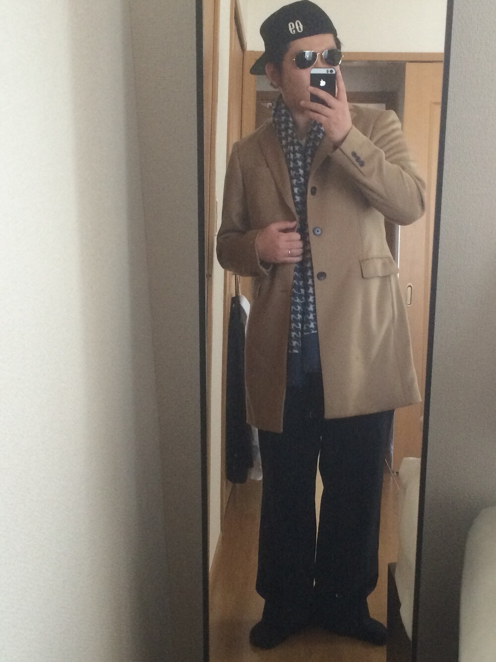 ブラック系のスラックス、ブラック系のブーツ、ベージュ系のチェスターコートを着用したメンズの秋コーディネートの1枚目の写真