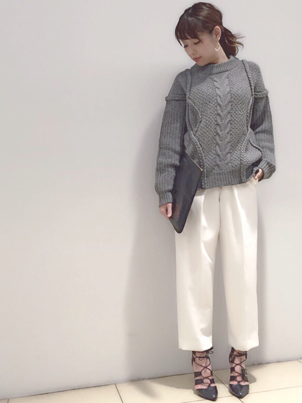 グレー系のニット/セーター、ブラック系のクラッチバッグ、ホワイト系のその他パンツを着用したレディースの秋コーディネートの1枚目の写真