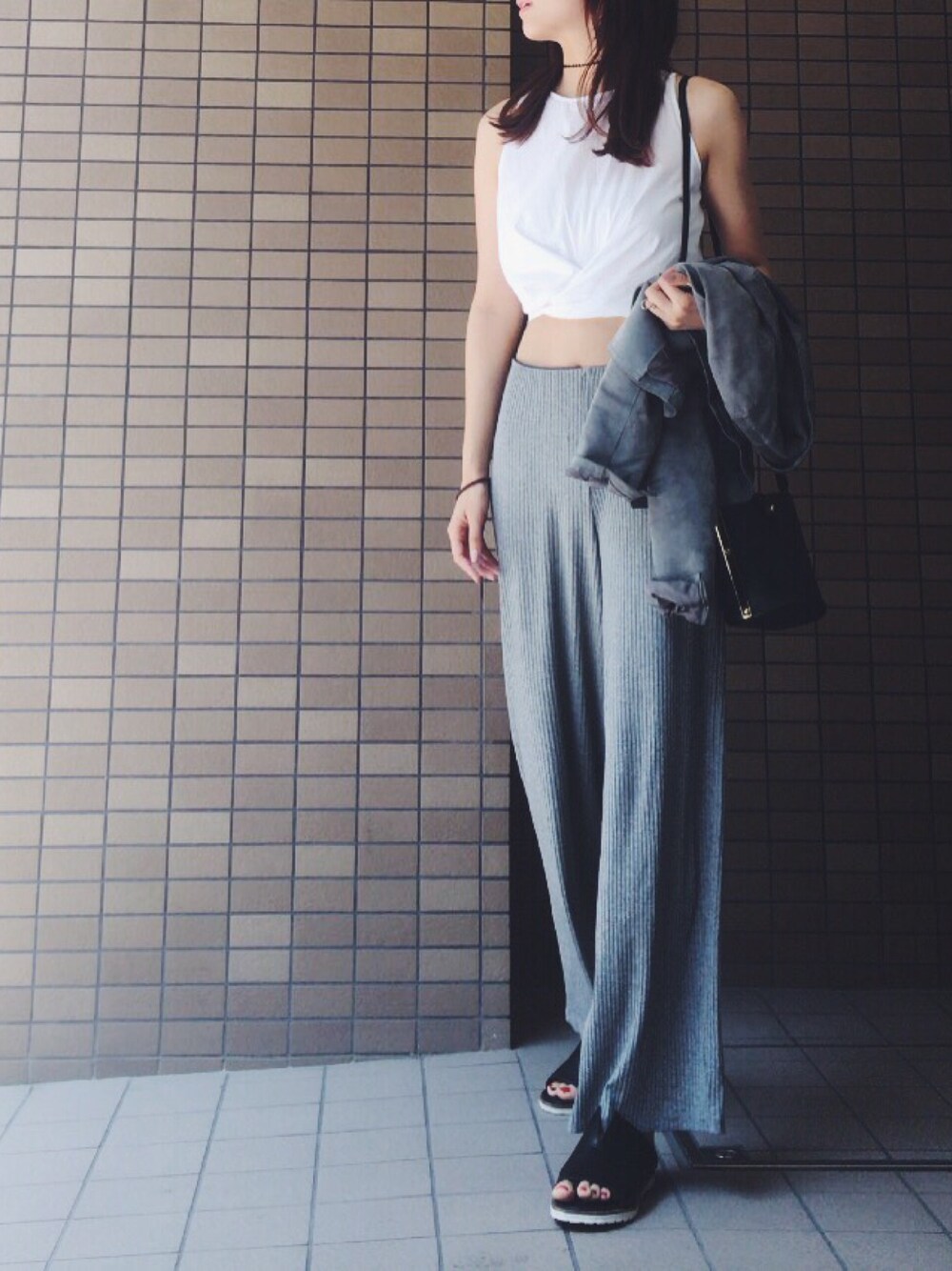 グレー系のその他パンツ、ホワイト系のトップス、ブラック系のサンダルを着用したレディースの夏コーディネートの1枚目の写真